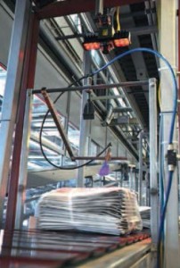 Die Verpackungsfolie sorgt für starke Reflexionen über den darunter zu lesenden Codes. In luftiger höhe richtet das Cognex ID-Lesegrät im Druckhaus Axel Springer sein scharfes Auge auf die schnellen Zeitungsbündel.
